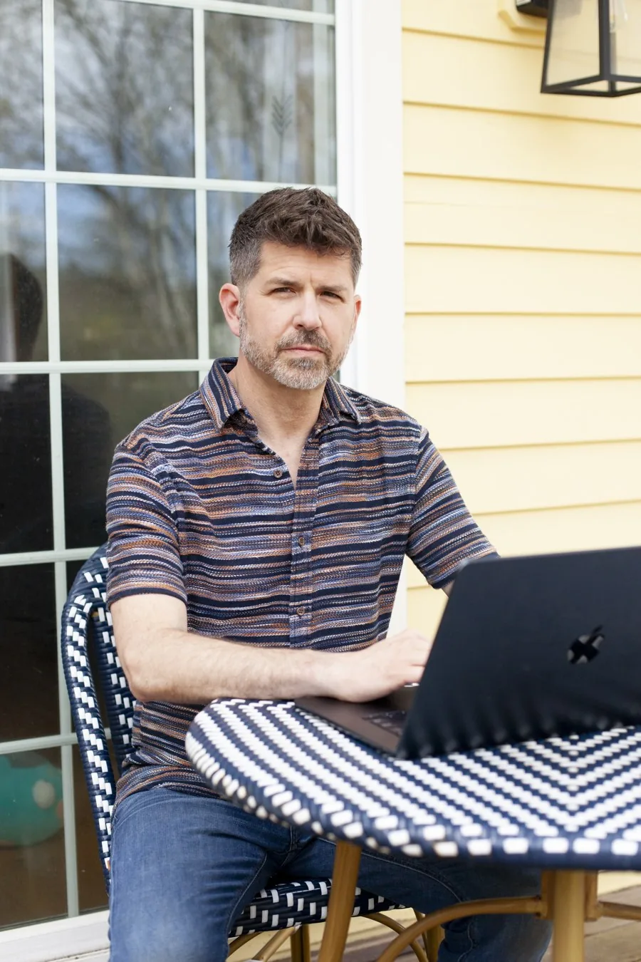 Jason Cianciotto seated at a laptop on a porch.