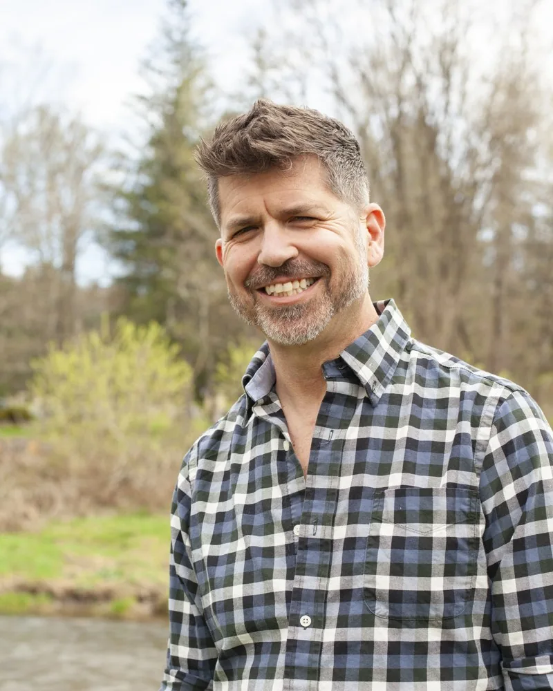 Jason Cianciotto smiling outdoors in a checked shirt.